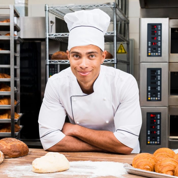 portrait-smiling-young-male-baker-standing-table-with-fresh-croissant-loaf-bread_23-2148189041-1